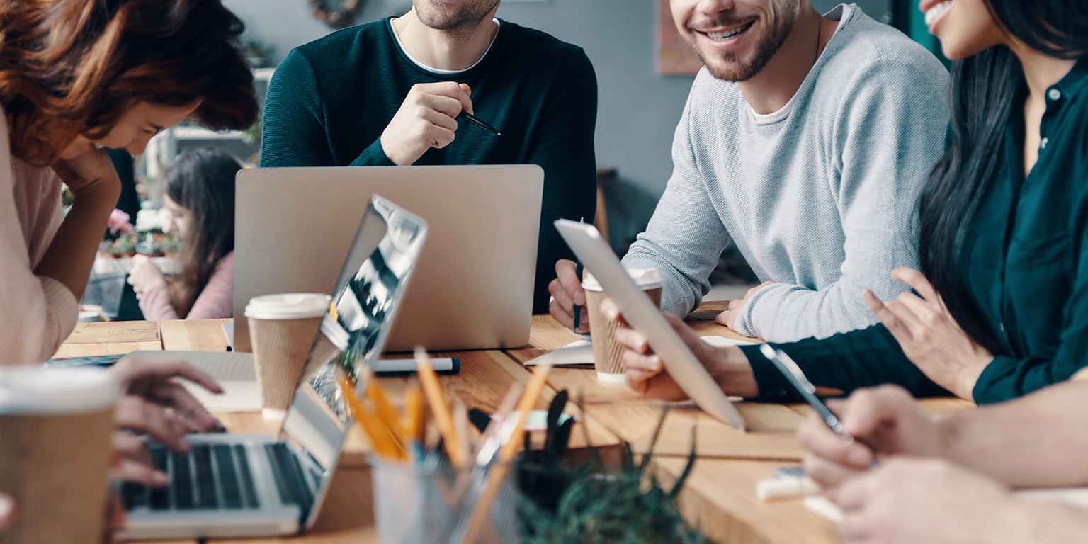 marketing team sitting around table with laptops