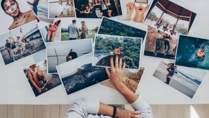 Overhead image of a person selecting photo prints from a collection scattered across a desktop