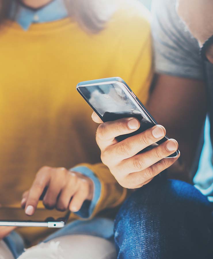 A person using a tablet and another person using a mobile phone