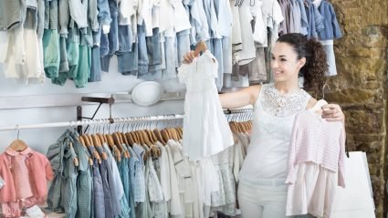 A woman comparing two baby outfits in a clothing store