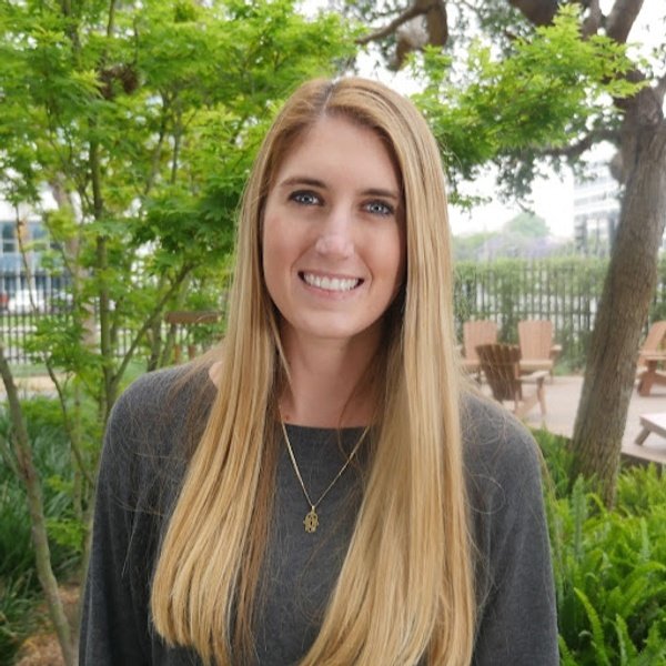 Blonde woman in front of leafy background