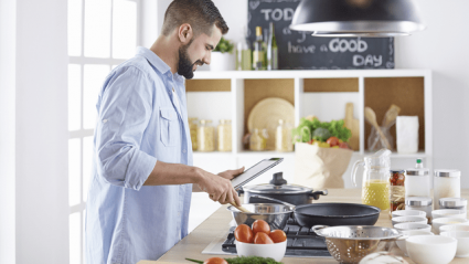 man reading recipe and cooking from home